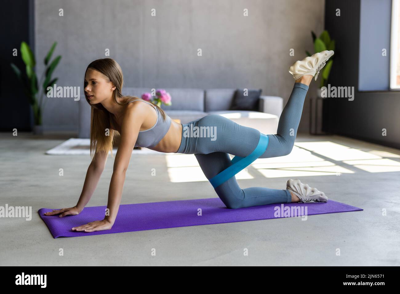 Young woman exercising with an elsatic band on the floor at home Stock Photo