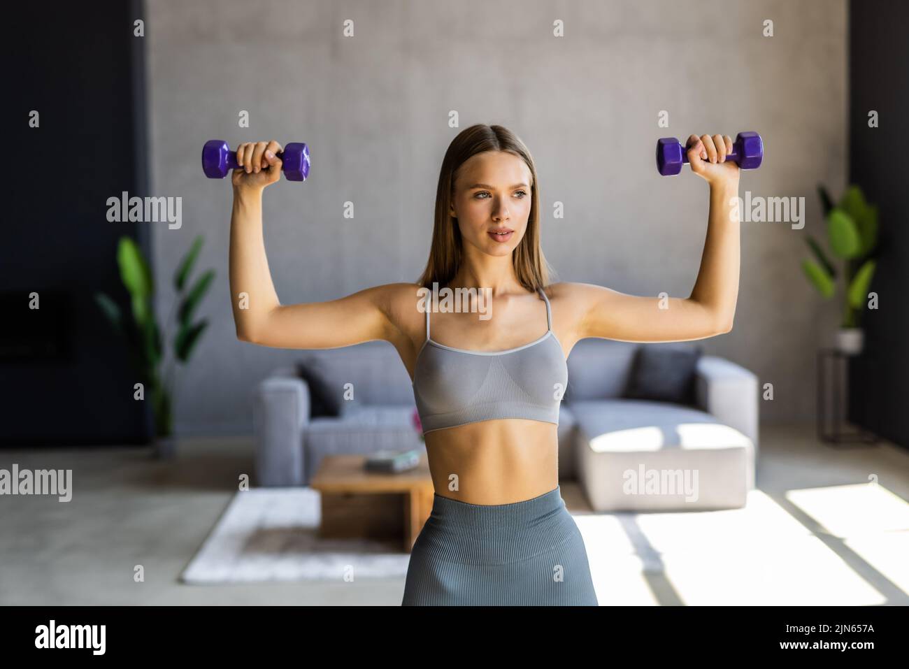 Fitness at home concept. Smiling young woman on mat with sports equipment at home. Stock Photo