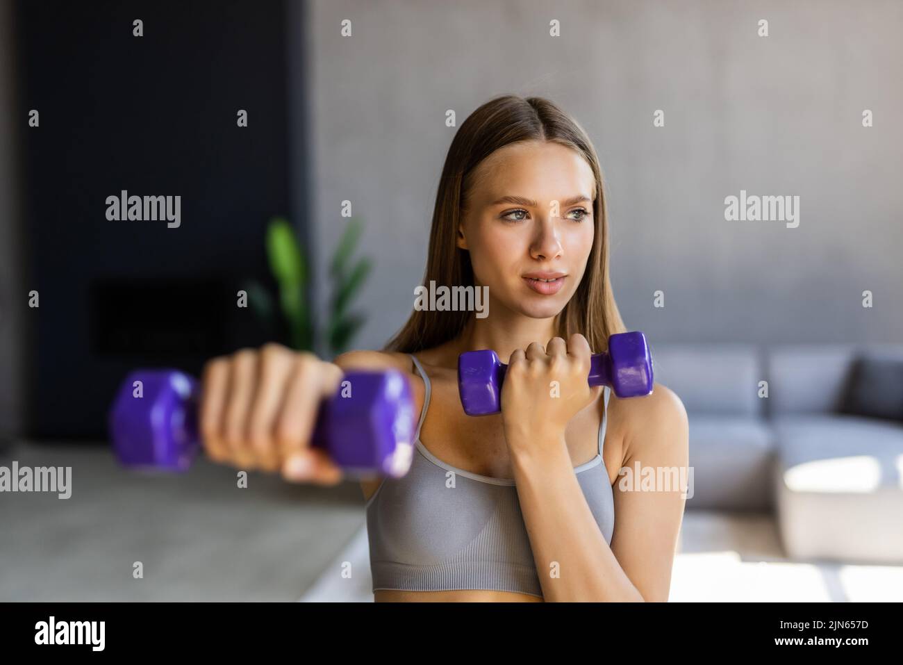 Fitness at home concept. Smiling young woman on mat with sports equipment at home. Stock Photo