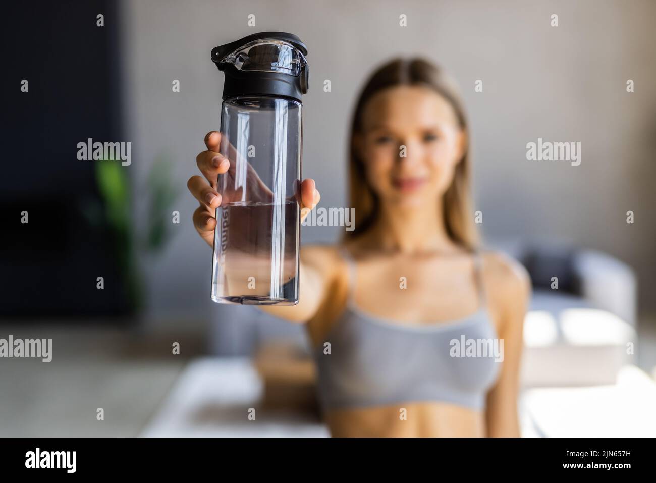 Keep hydrated. Young woman drinking water on yoga mat at home Stock Photo