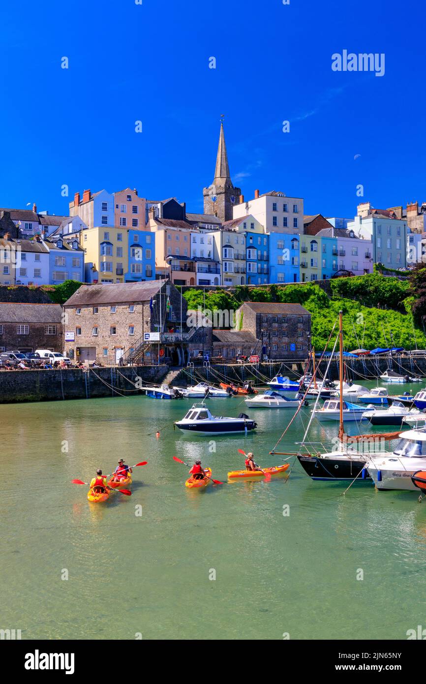 A group of sea kayakers in the picturesque sheltered harbour, overlooked by rows of colourful houses in Tenby, Pembrokeshire, Wales, UK Stock Photo