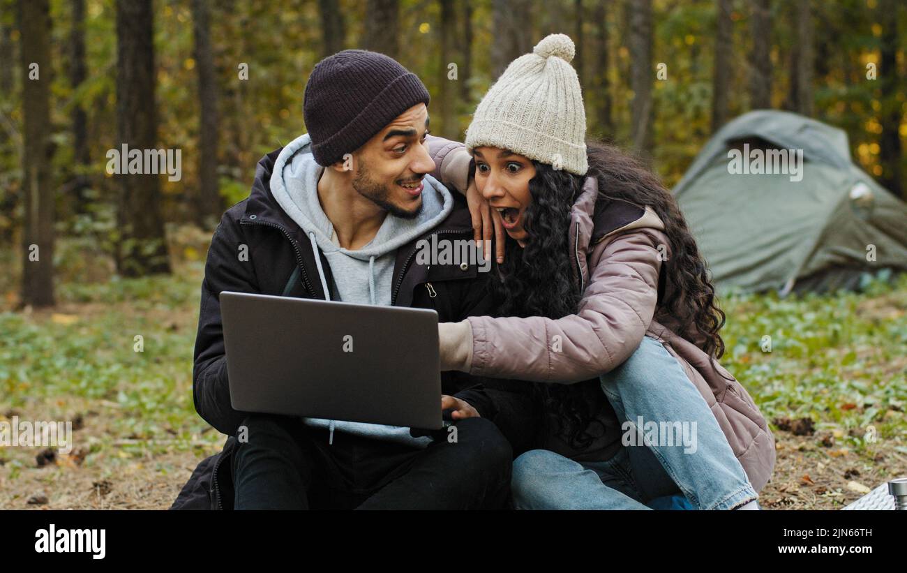 Young happy couple in love tourists sit outdoors in campsite look at
