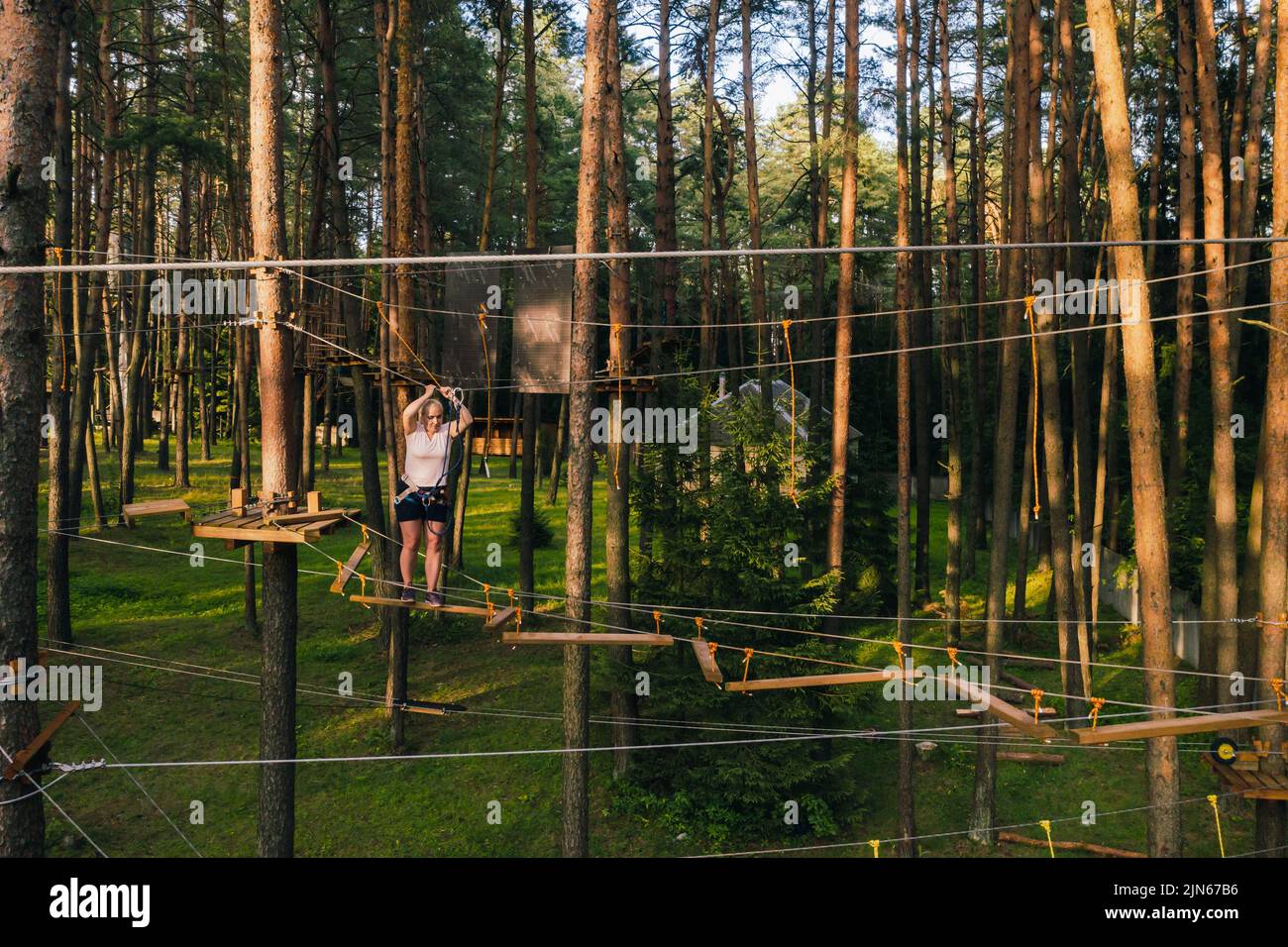 A woman overcomes an obstacle in a rope town. A woman in a forest rope ...