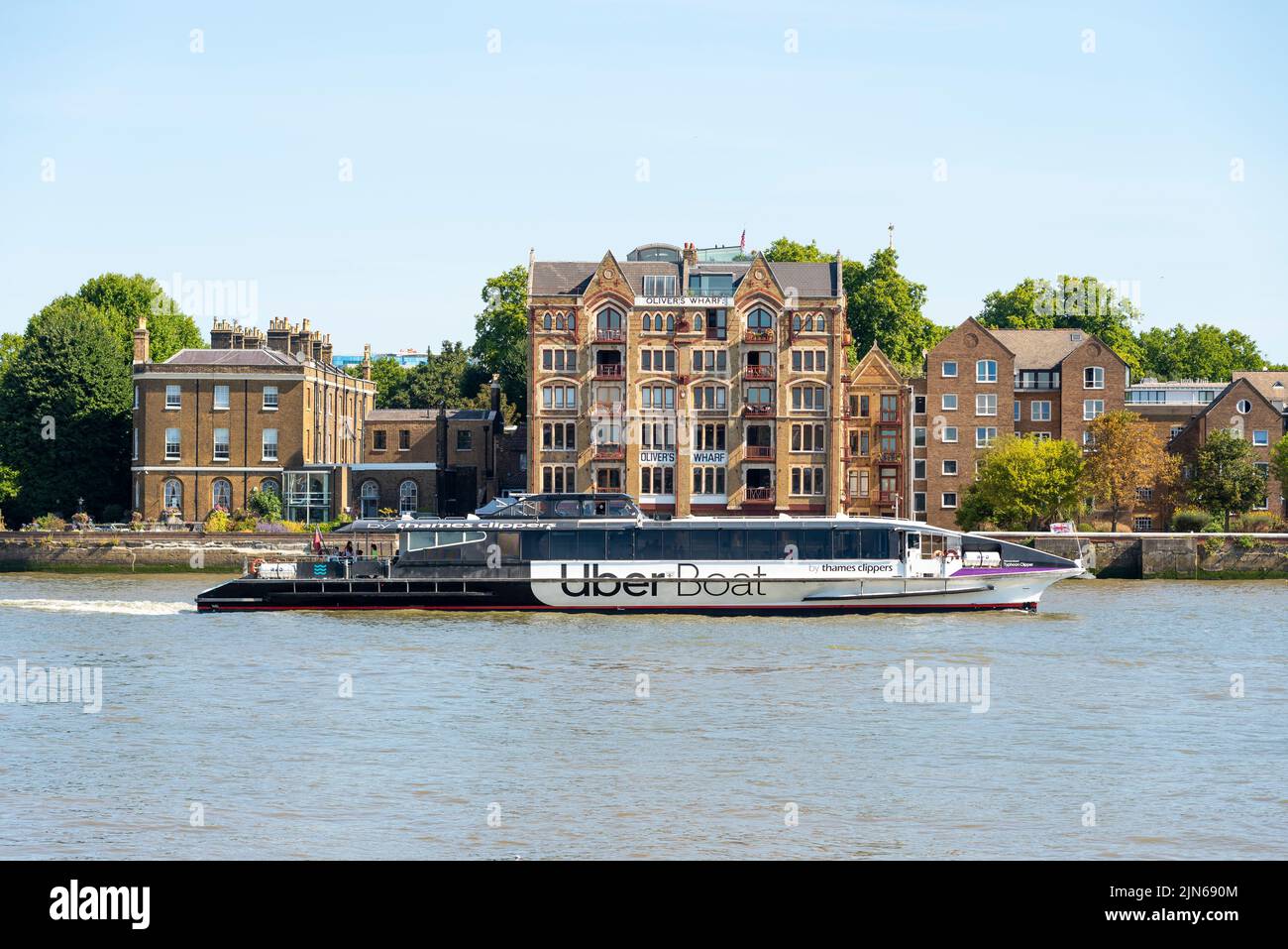 Oliver's Wharf building in the Pool of London on the River Thames. Former warehouse, developed into luxury riverfront apartments. Uber Boat passing Stock Photo