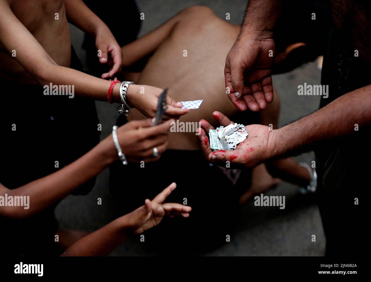 A Shi'ite Muslim mourner collects razor blades from other mourners during a Muharram procession marking Ashura in Ahmedabad, India, August 9, 2022. REUTERS/Amit Dave Stock Photo