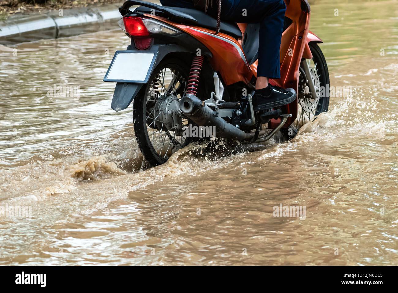 Man ride motorcycle passing through flooded road. Riding motorbike on