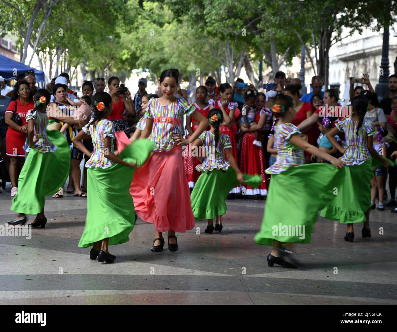 Landscape with young Cuban girls wearing colorful costumes dancing folkloric dances along the