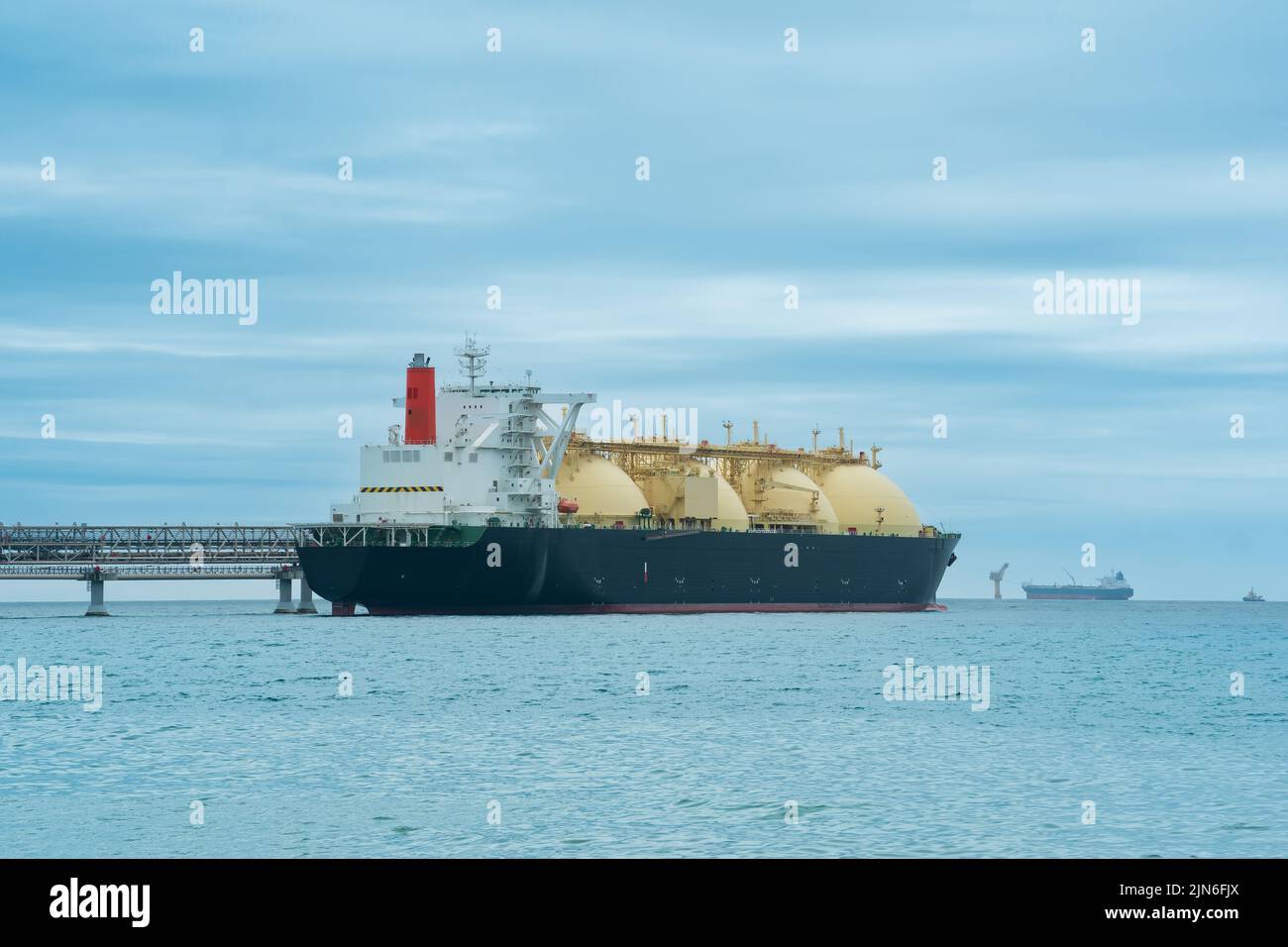 liquefied natural gas carrier tanker during loading at an LNG offshore terminal, in the distance
