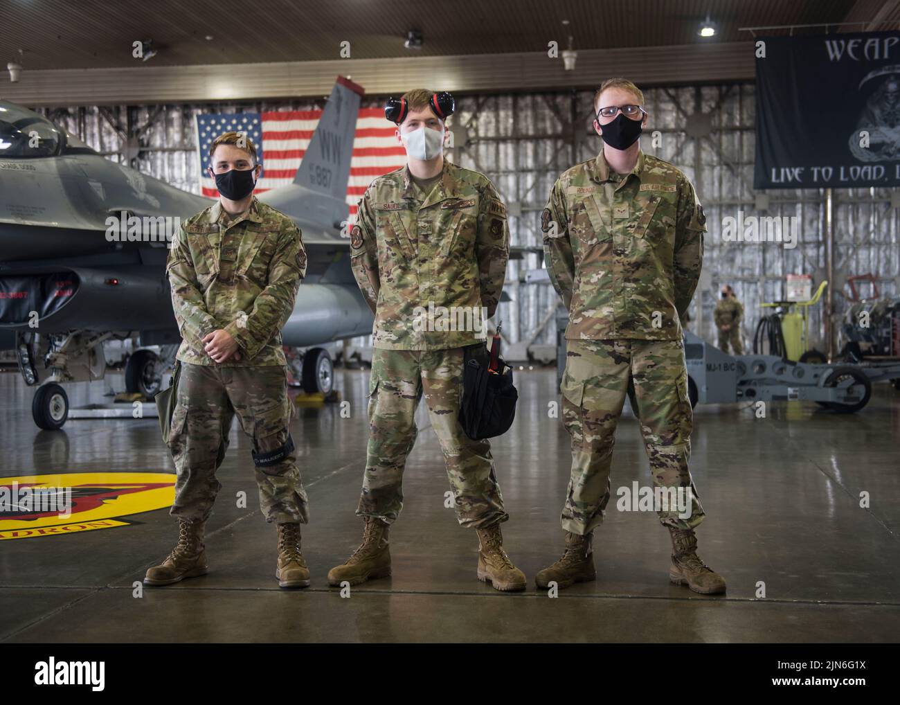U.S. Air Force Staff Sgt. David Botterill (left), a weapons load team chief, Airmen 1st Class Braedon Sauer (center) and Cole Rounds (right), weapons load team members, from the 13th Aircraft Maintenance Unit, stand in front of an F-16 Fighting Falcon during the second quarter load competition at Misawa Air Base, Japan, July 16, 2021. It takes three members to prepare the aircraft, checklist the technical orders and attach the weapons onto the aircraft during the load competition as efficiently as possible. (U.S. Air Force photo by Airman 1st Class Leon Redfern) Stock Photo