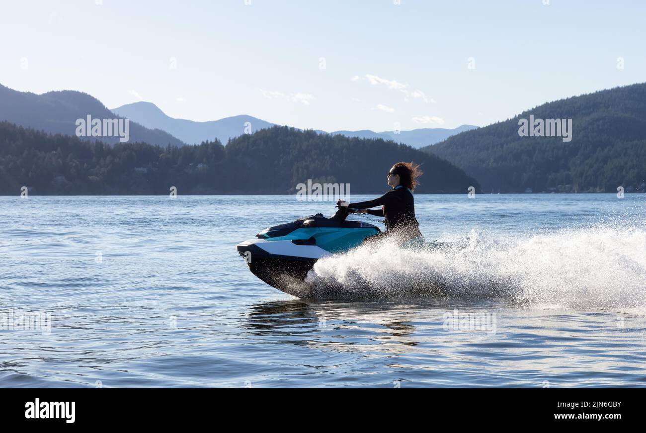 Adventurous Caucasian Woman on Water Scooter riding in the Ocean Stock Photo