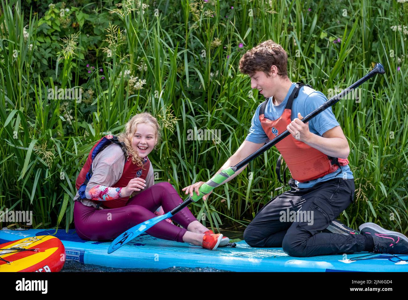 Young adults canoeing on a canal and jumping in Stock Photo