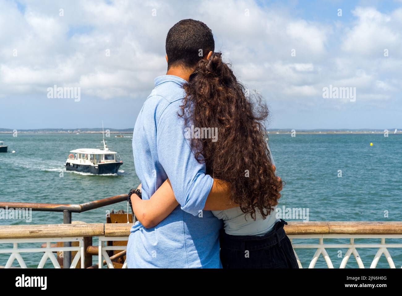 A couple embraced on the pier looks at the horizon, facing the Cap Ferret. Arcachon beach, the Belisaire pier, the embarkations, the lovers, the bathers, a day at the beach. August 04, 2022. Photo by Patricia Huchot-Boissier/ABACAPRESS.COM Stock Photo