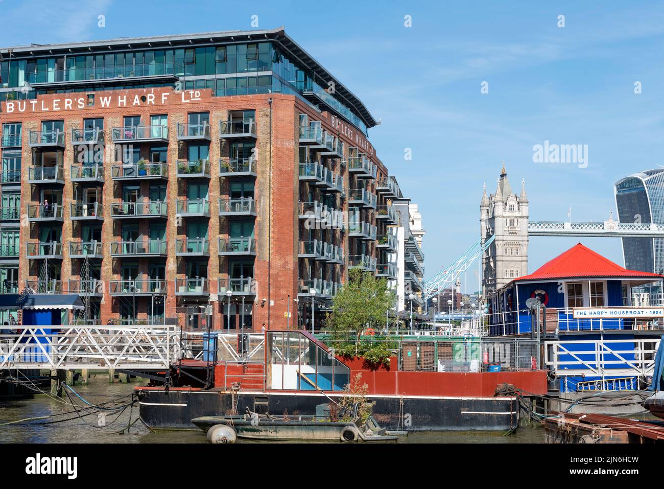 Butler's Wharf, historic developed building at Shad Thames on south bank of the River Thames, near London's Tower Bridge. The Harpy Houseboat on river Stock Photo