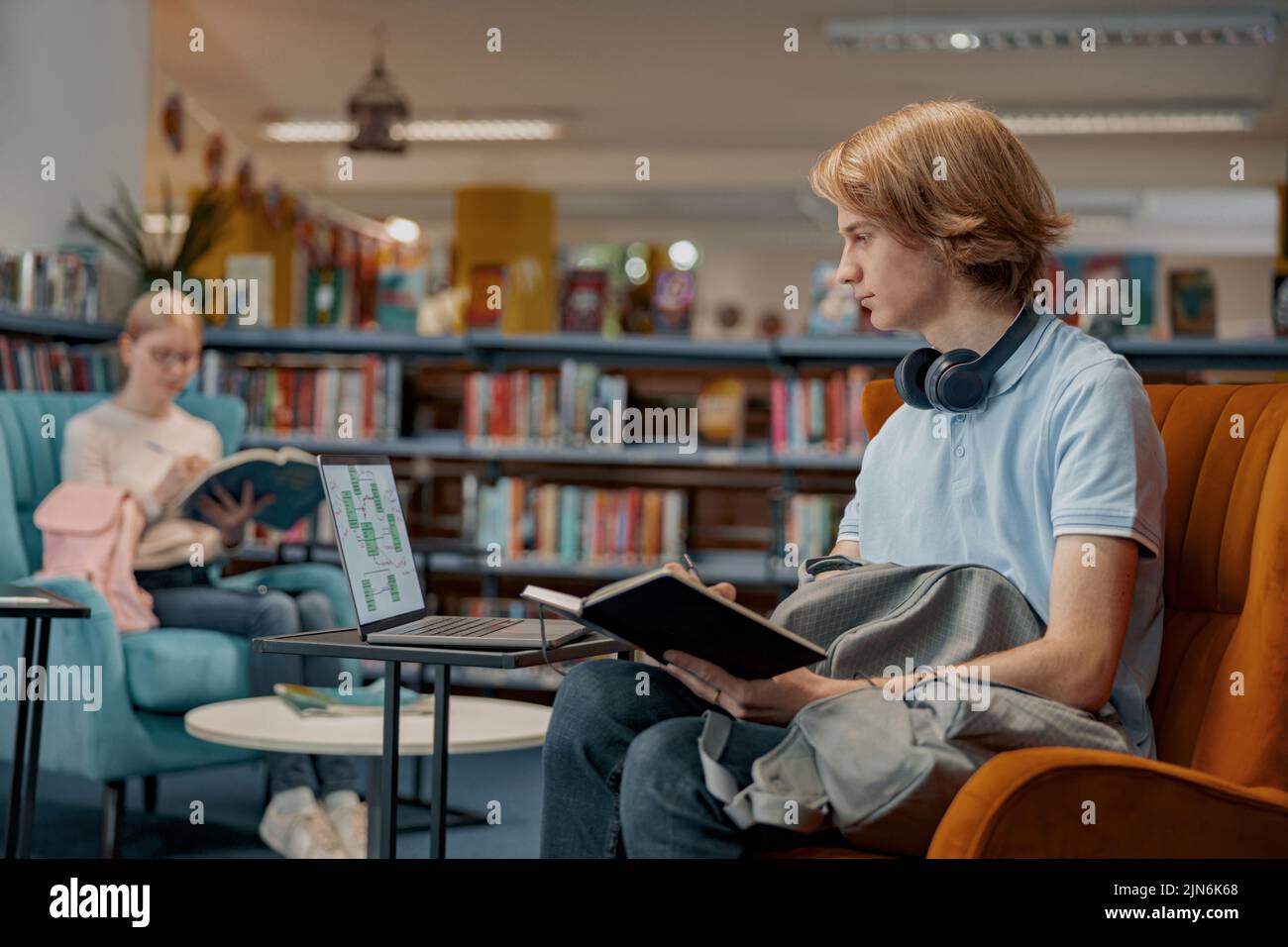 Friends student sit near bookshelves in library and studying. Prepearing for exam Stock Photo