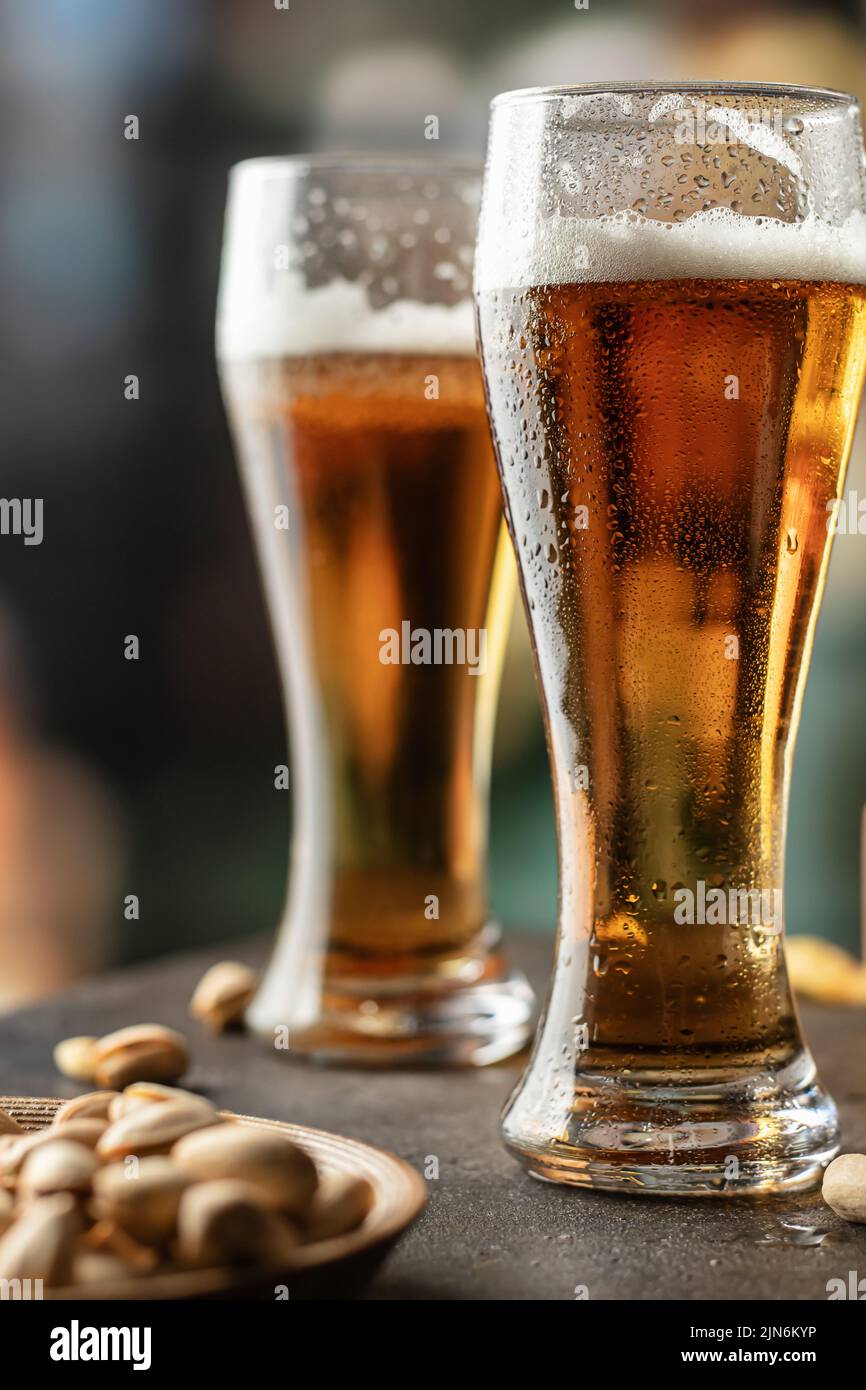Full glasses of light beer with drops on the side in bar close up. Alcohol, entertainment, traditional drinks, Oktoberfest atmosphere concept. Vertica Stock Photo