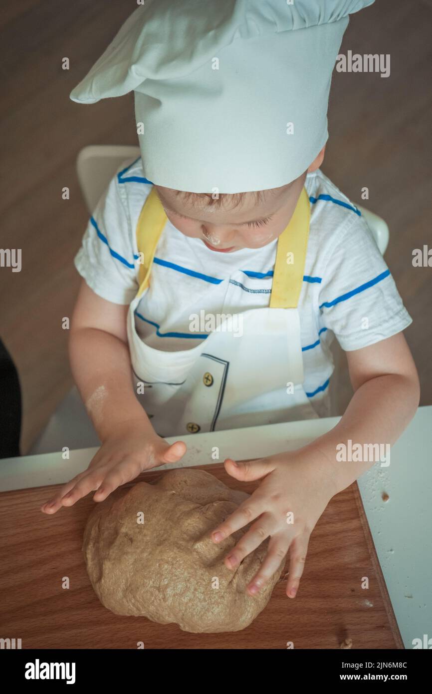 A guy in a chef's outfit kneads the dough Stock Photo