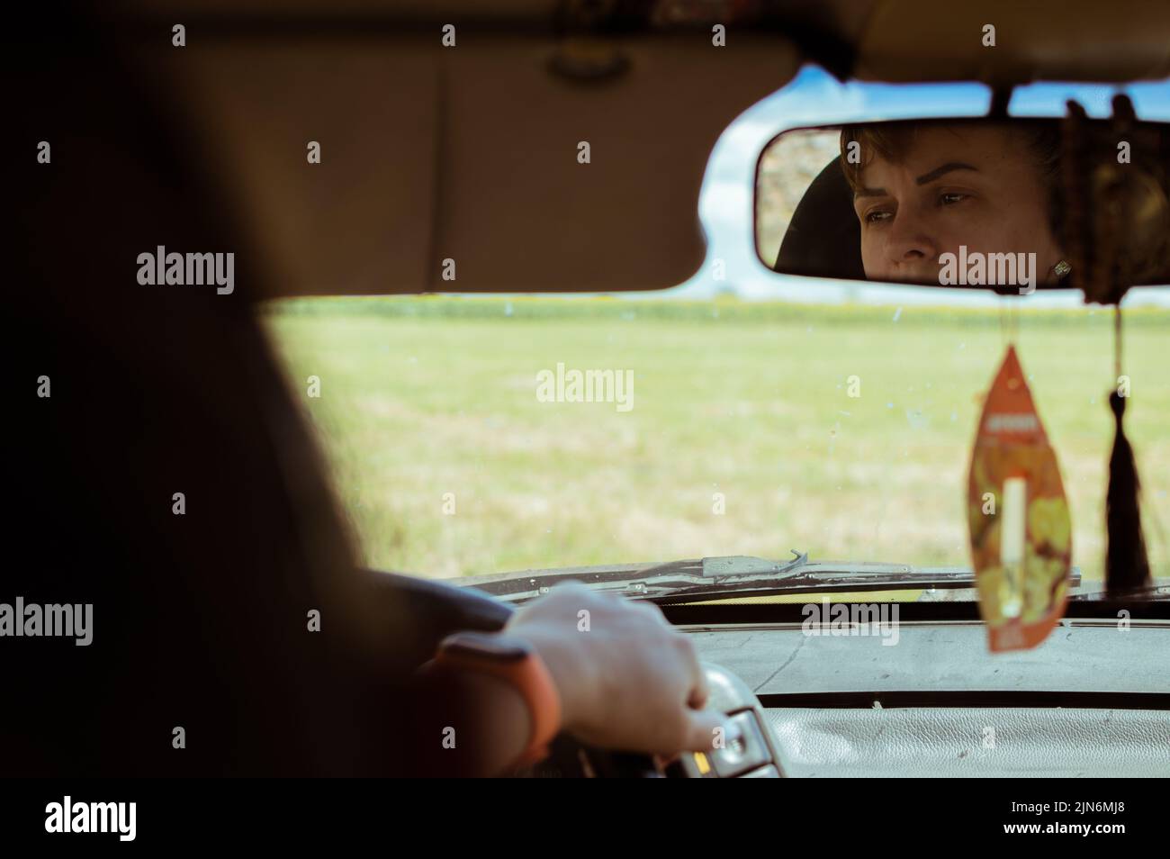 Woman looks thoughtfully in car mirror Stock Photo