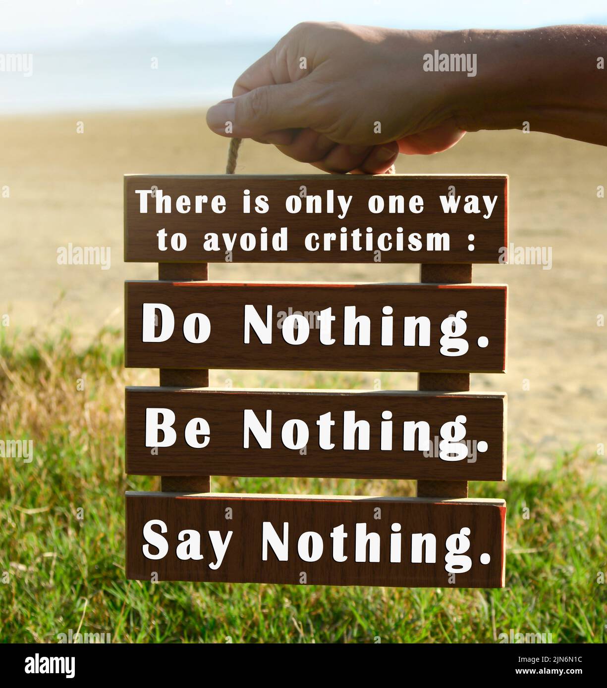 Hands holding wooden frame with motivational quote. Way to avoid criticism. Stock Photo