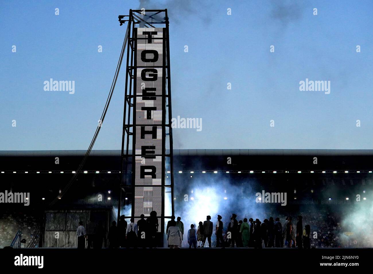 Performers on stage look up at a sign during the Closing Ceremony for