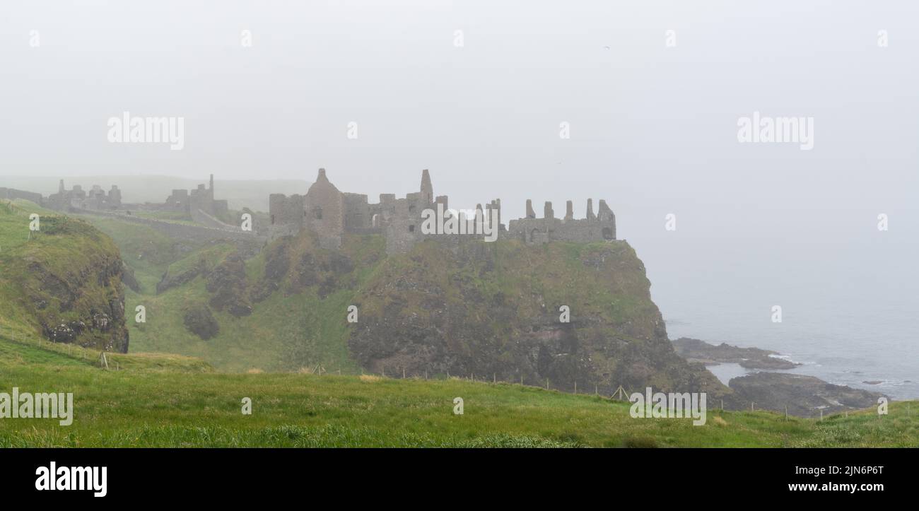 Portrush, United Kingdom - 9 July, 2022: panorama view of the ruins of Dunluce Castle on a foogy day on the north coast of Ireland Stock Photo