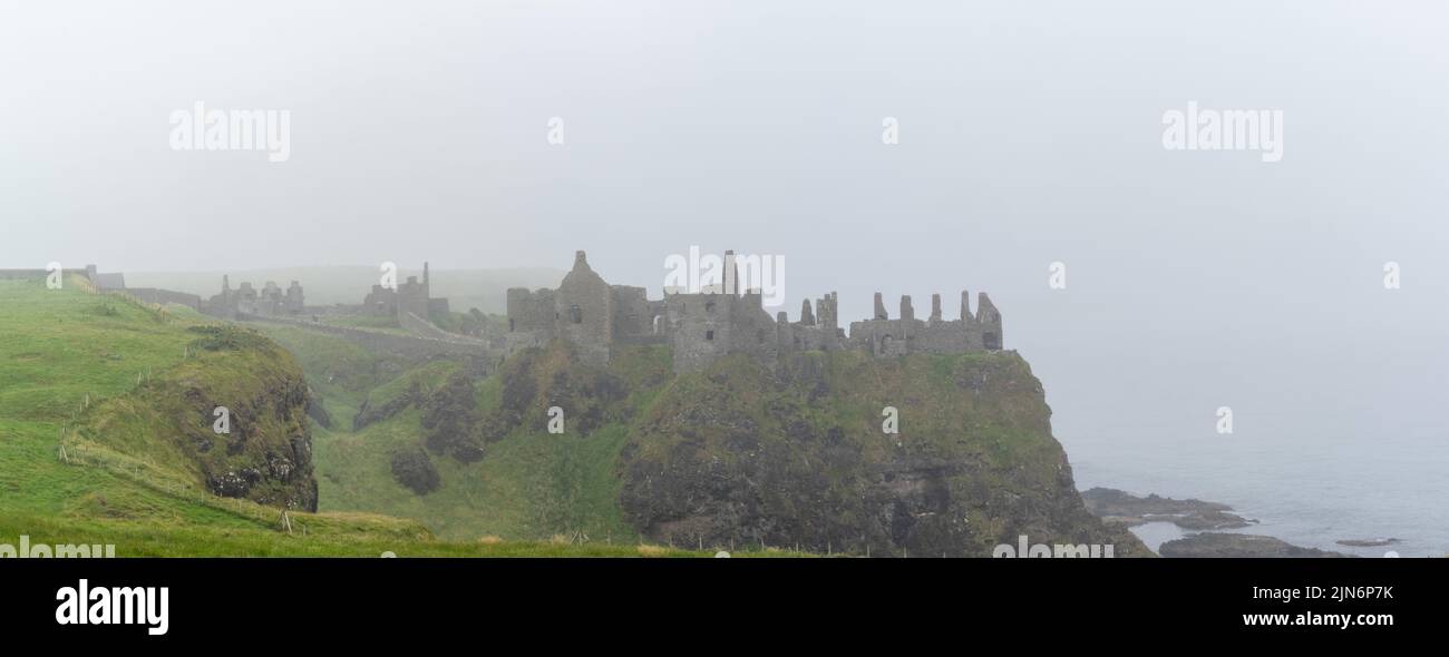 Portrush, United Kingdom - 9 July, 2022: panorama view of the ruins of Dunluce Castle on a foogy day on the north coast of Ireland Stock Photo