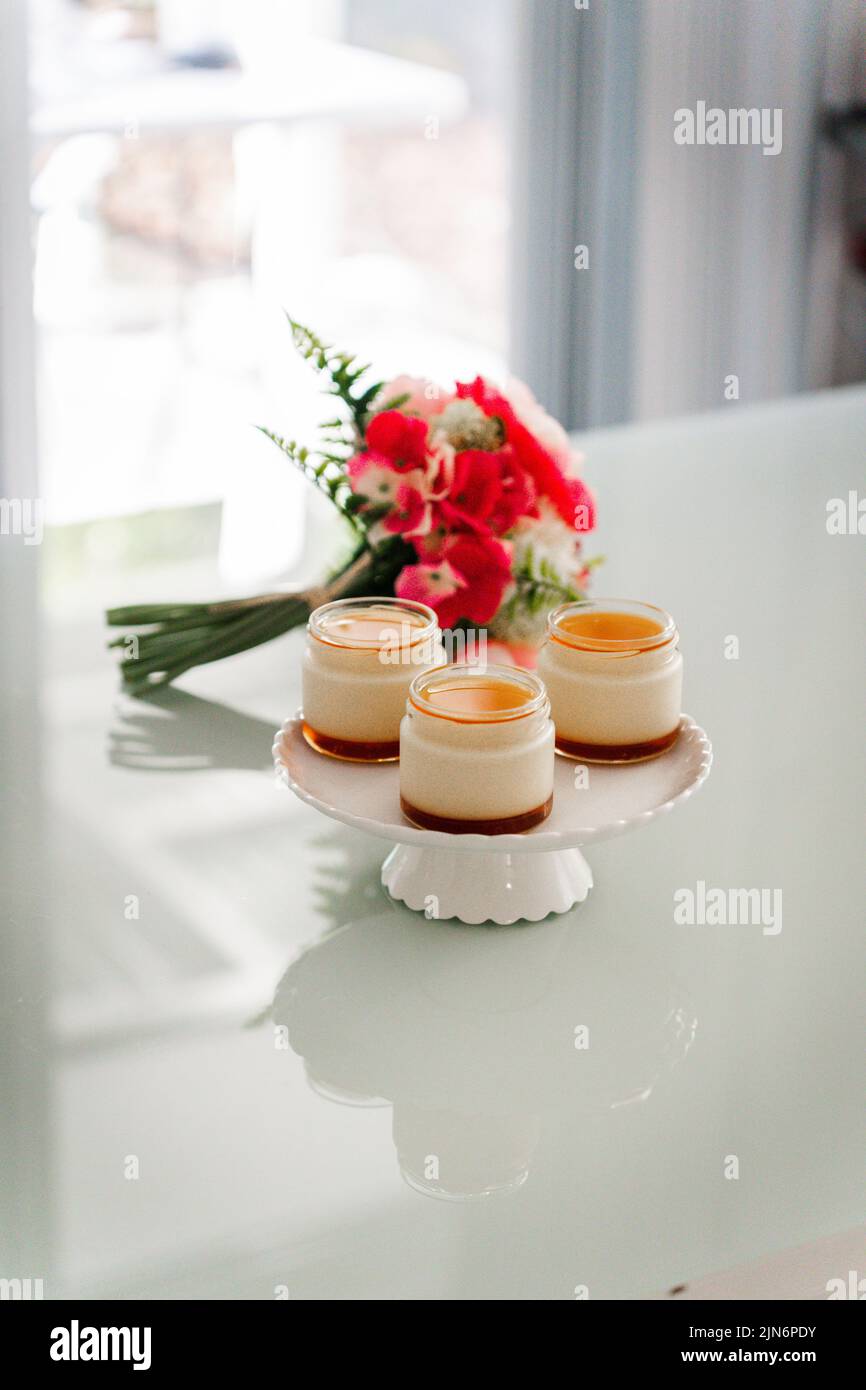 Mini dessert cups on a cake plate with a bouquet of flowers on a white