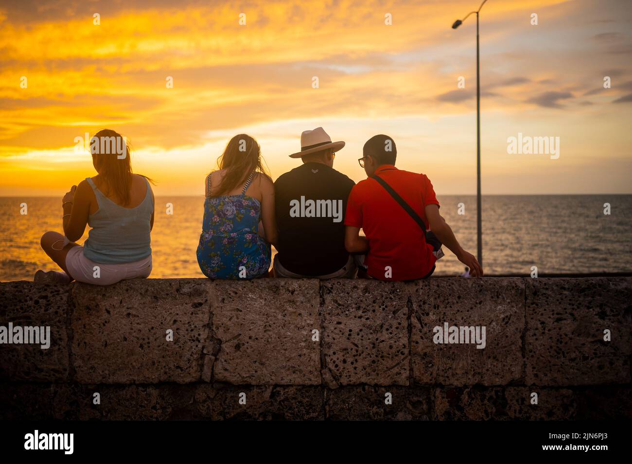 Visitors enjoy the sunset from atop the walls of the old city in Cartagena, Colombia Stock Photo