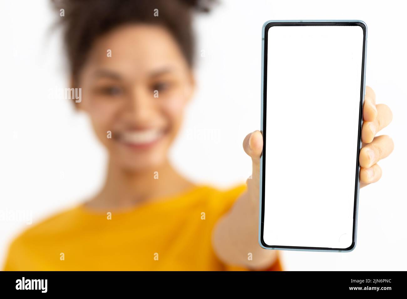 Portrait of young woman with mobile phone on white background Female with curly hair holding a smartphone Stock Photo