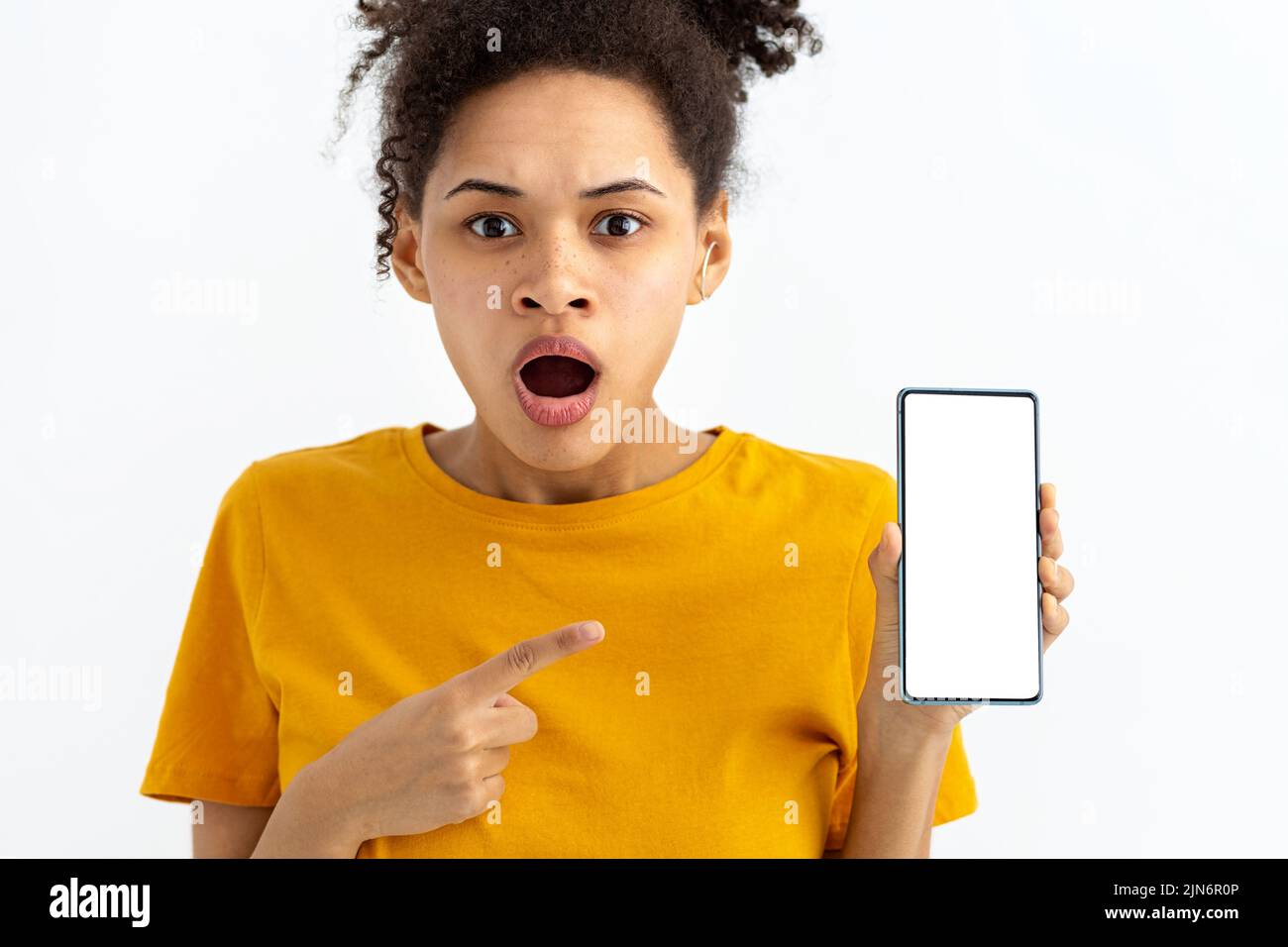 young surprised woman with mobile phone on white background looking at the camera Stock Photo