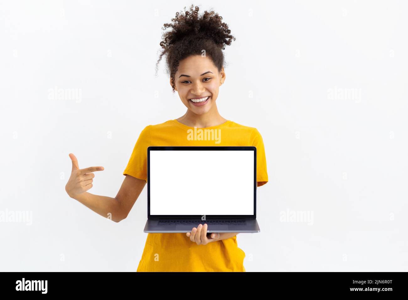young woman with laptop on white background Beautiful female points her finger at blank laptop screen Stock Photo