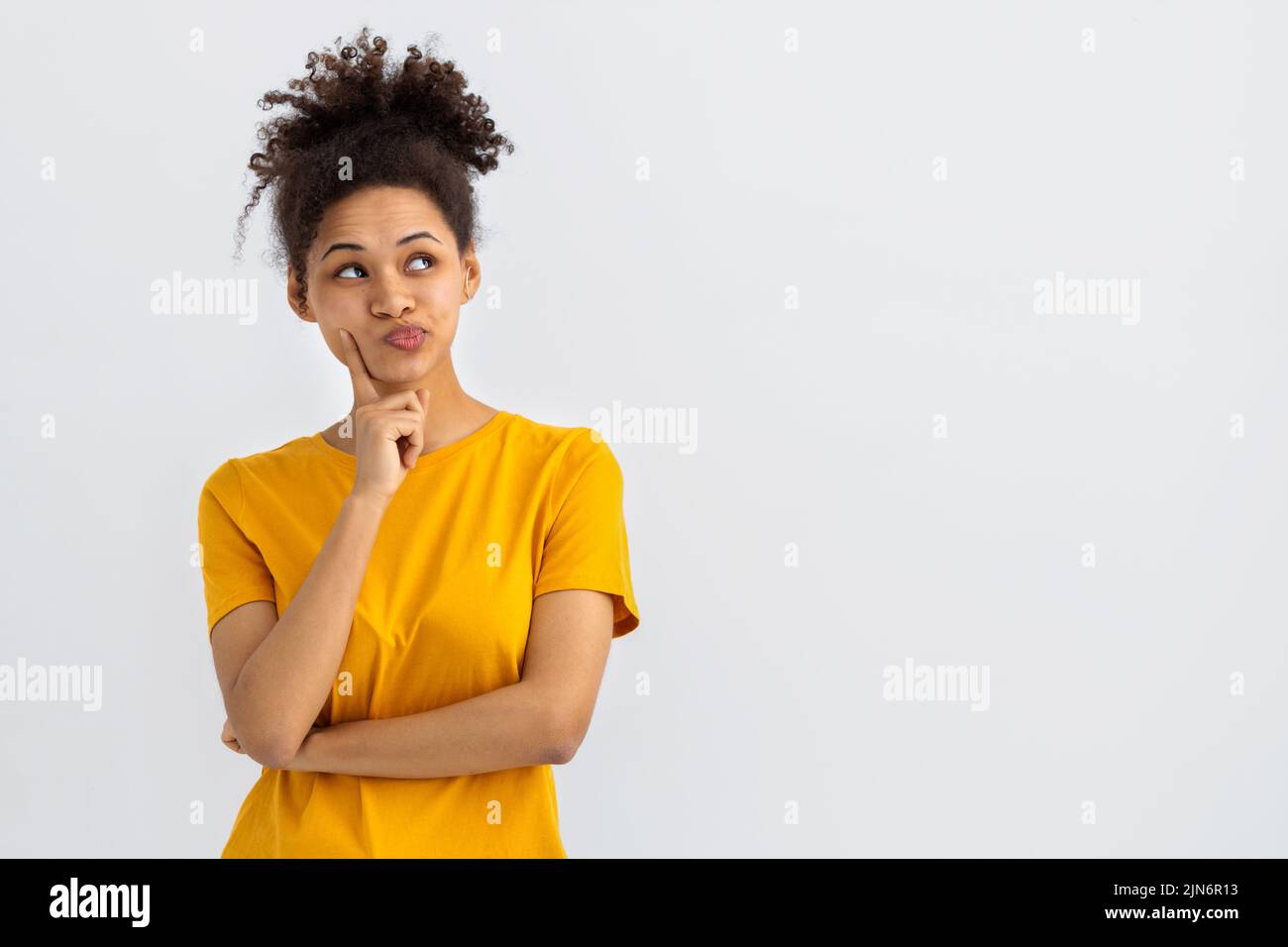 Young woman with curly hair on white background thinking an idea Stock Photo