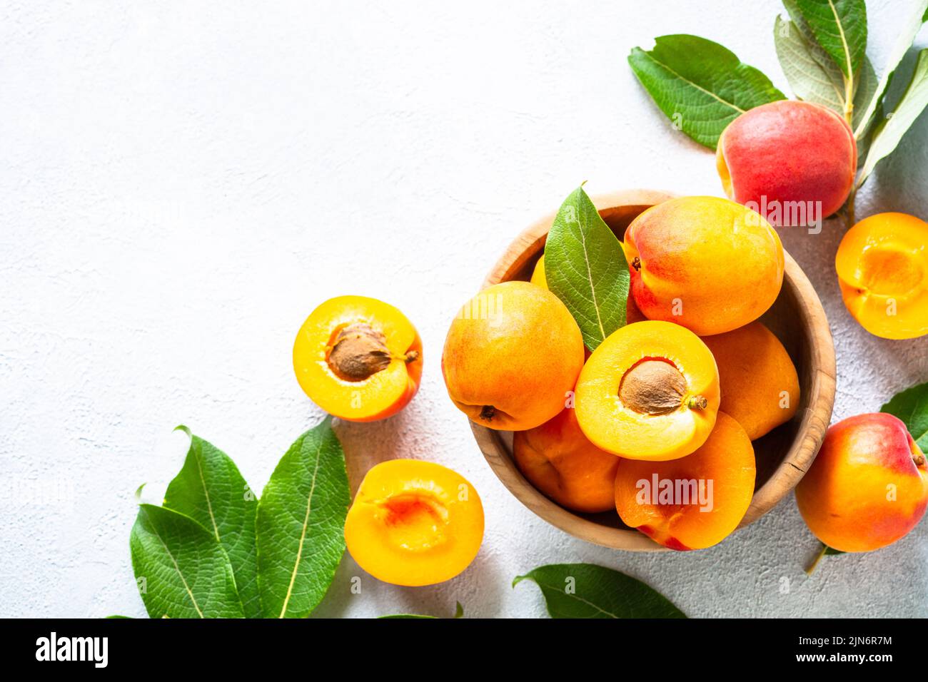 Fresh apricots with green leaves at white. Stock Photo