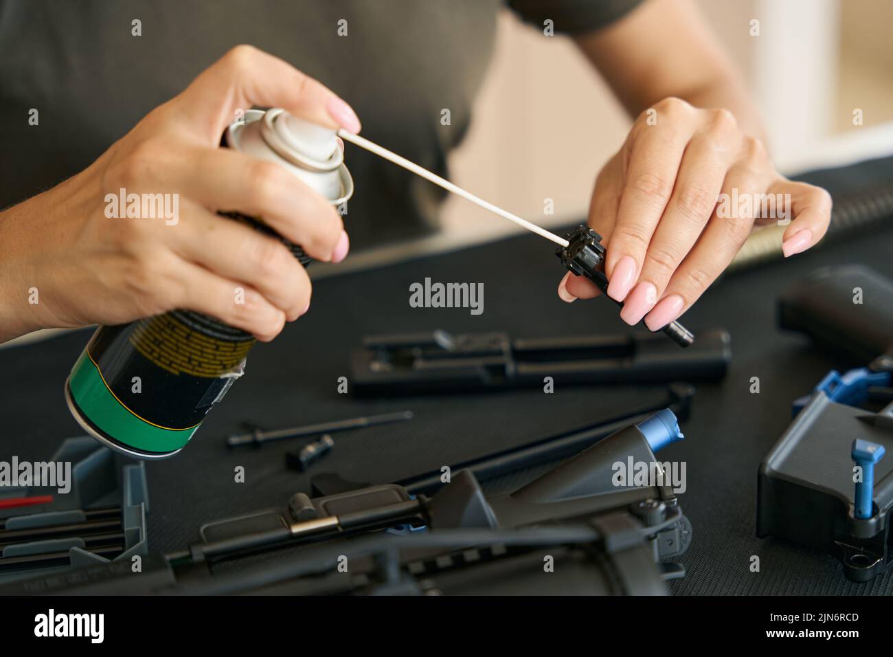 Military woman holds lubricant and part of machine gun in hands Stock