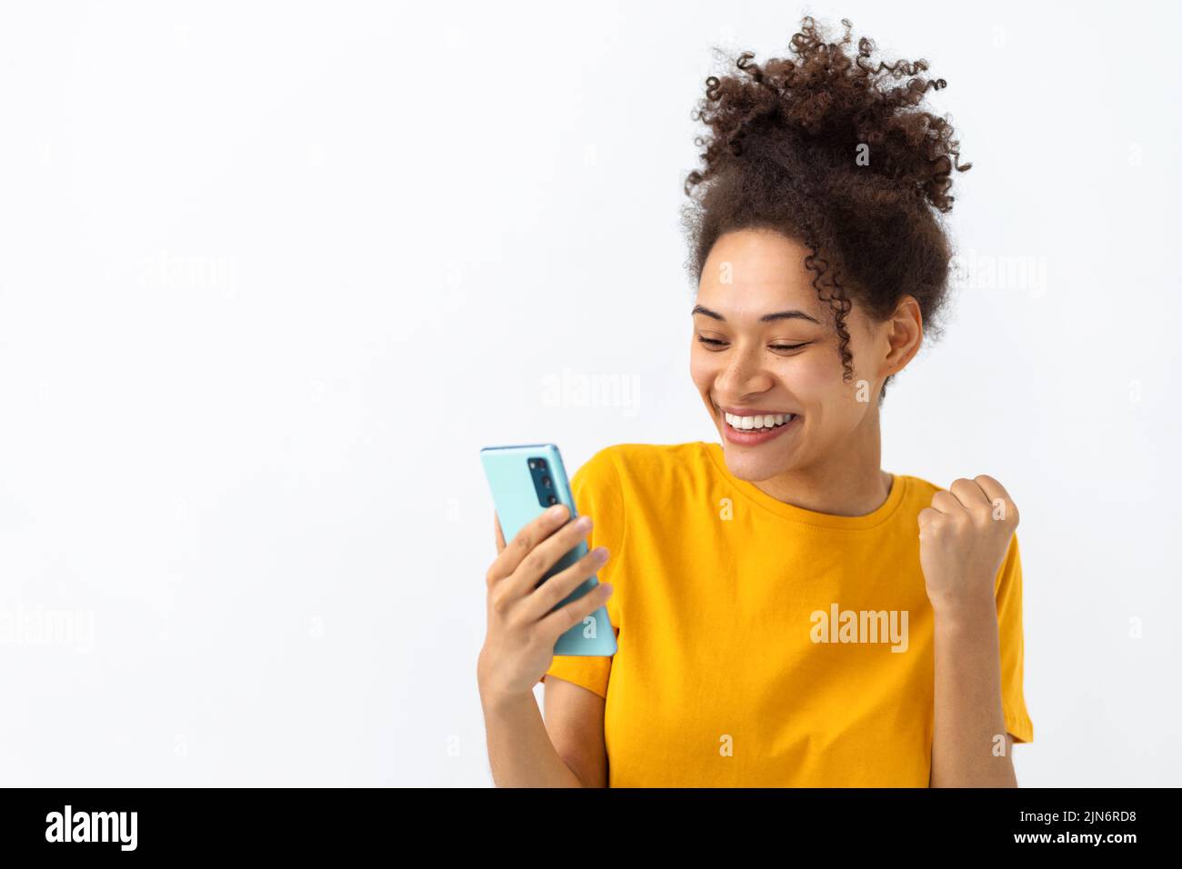 Excited young African American woman received good message on the mobile phone happy with great news Stock Photo