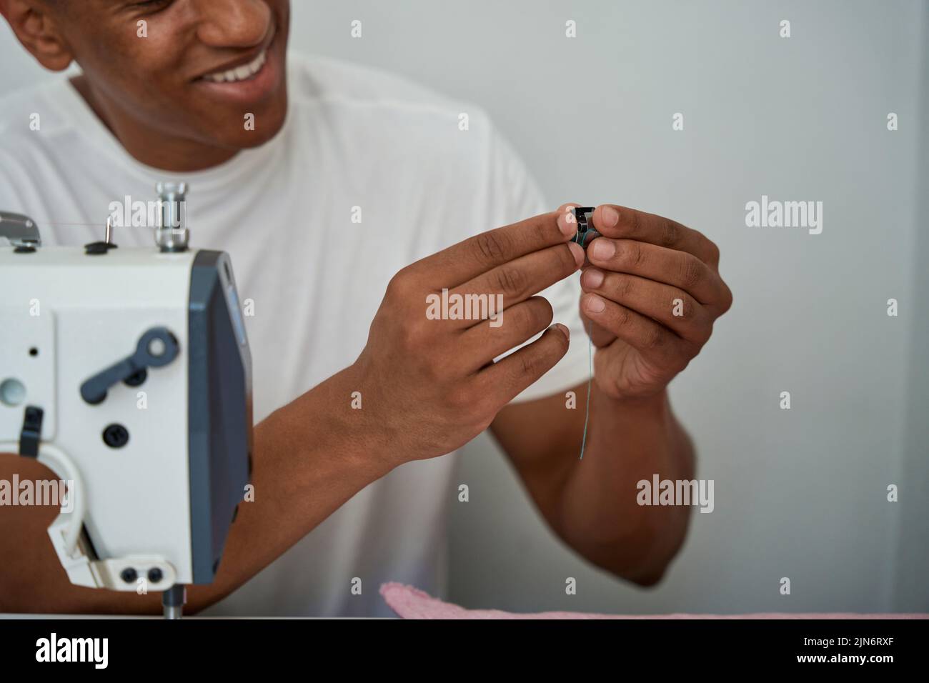 Smiling male tailor using sewing machine in atelier Stock Photo