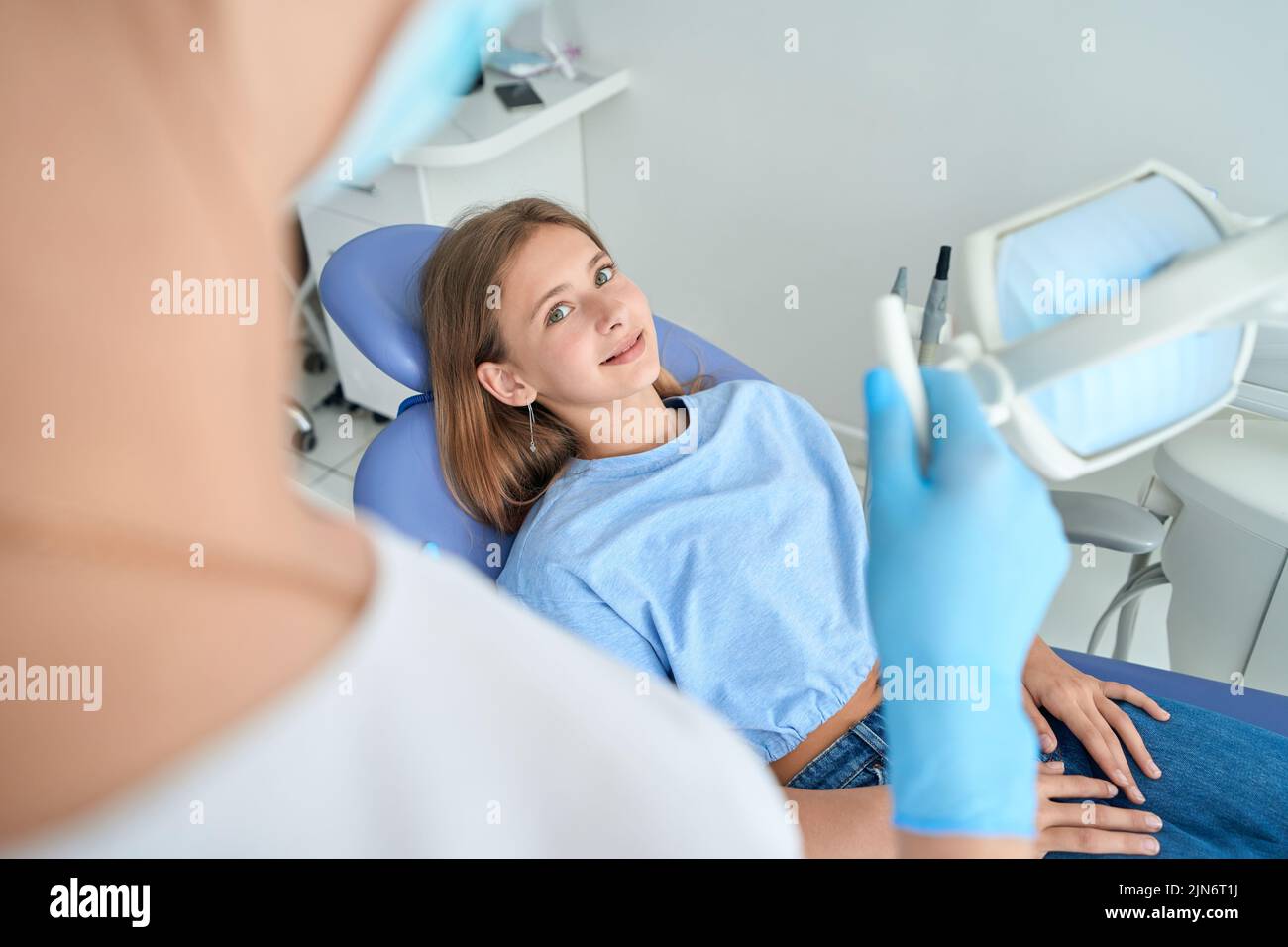 Adolescent girl listening to pediatric dentist during consultation Stock Photo