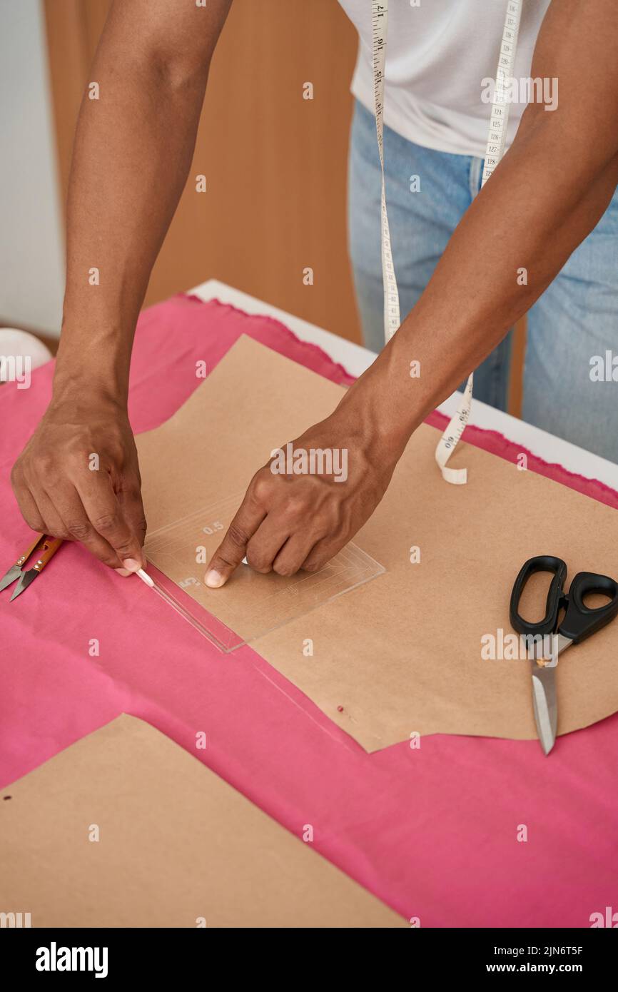 Male tailor doing patterns with chalk on pink fabric Stock Photo