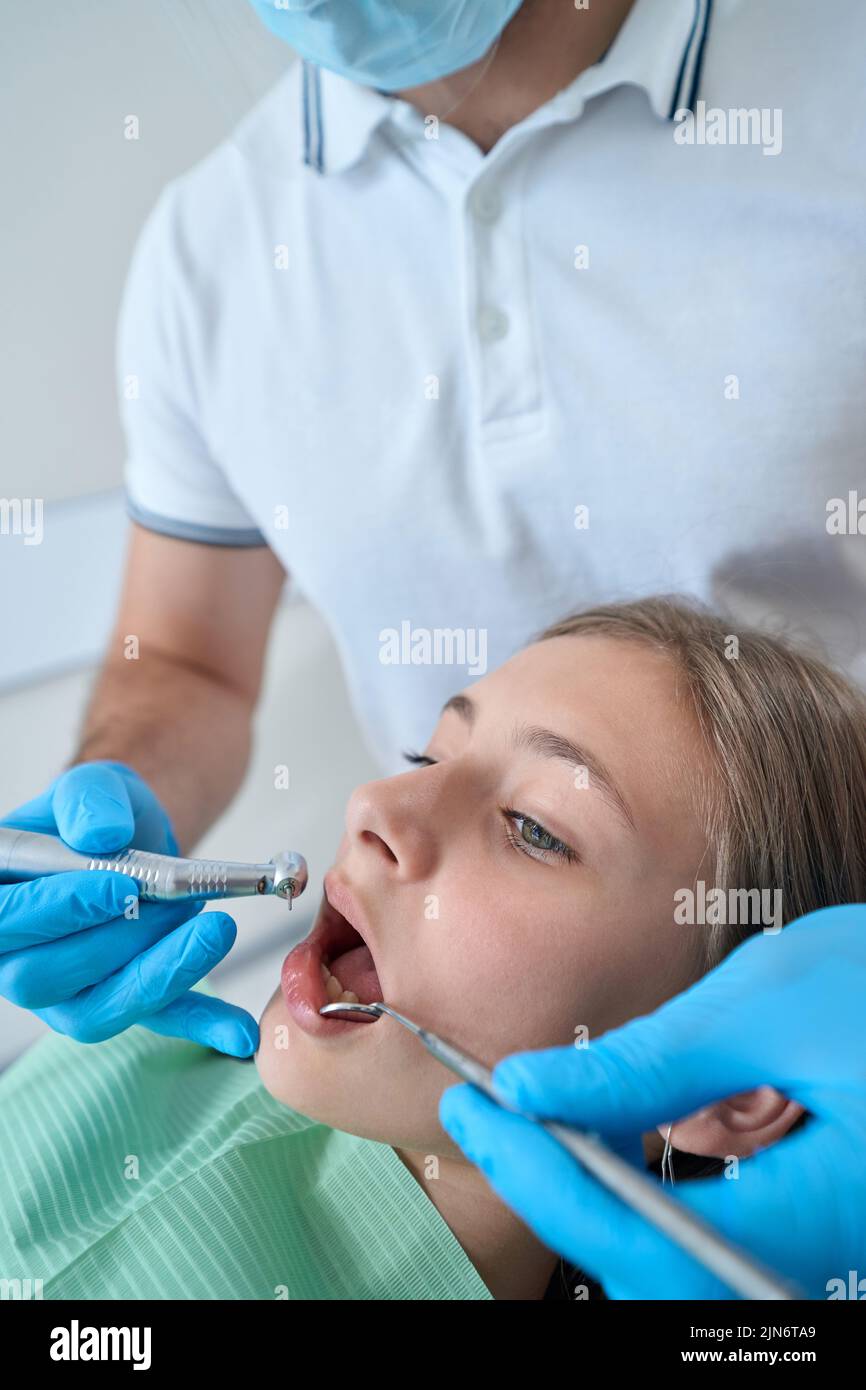 Professional pediatric dentist treating caries in teenage patient Stock