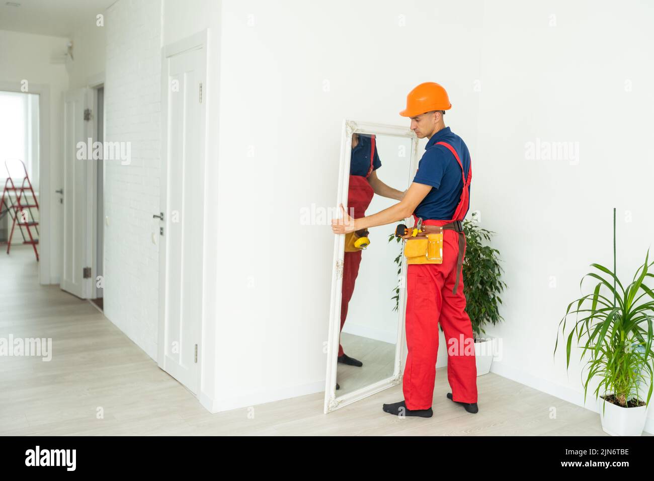 Man installing a mirror on wall Stock Photo Alamy