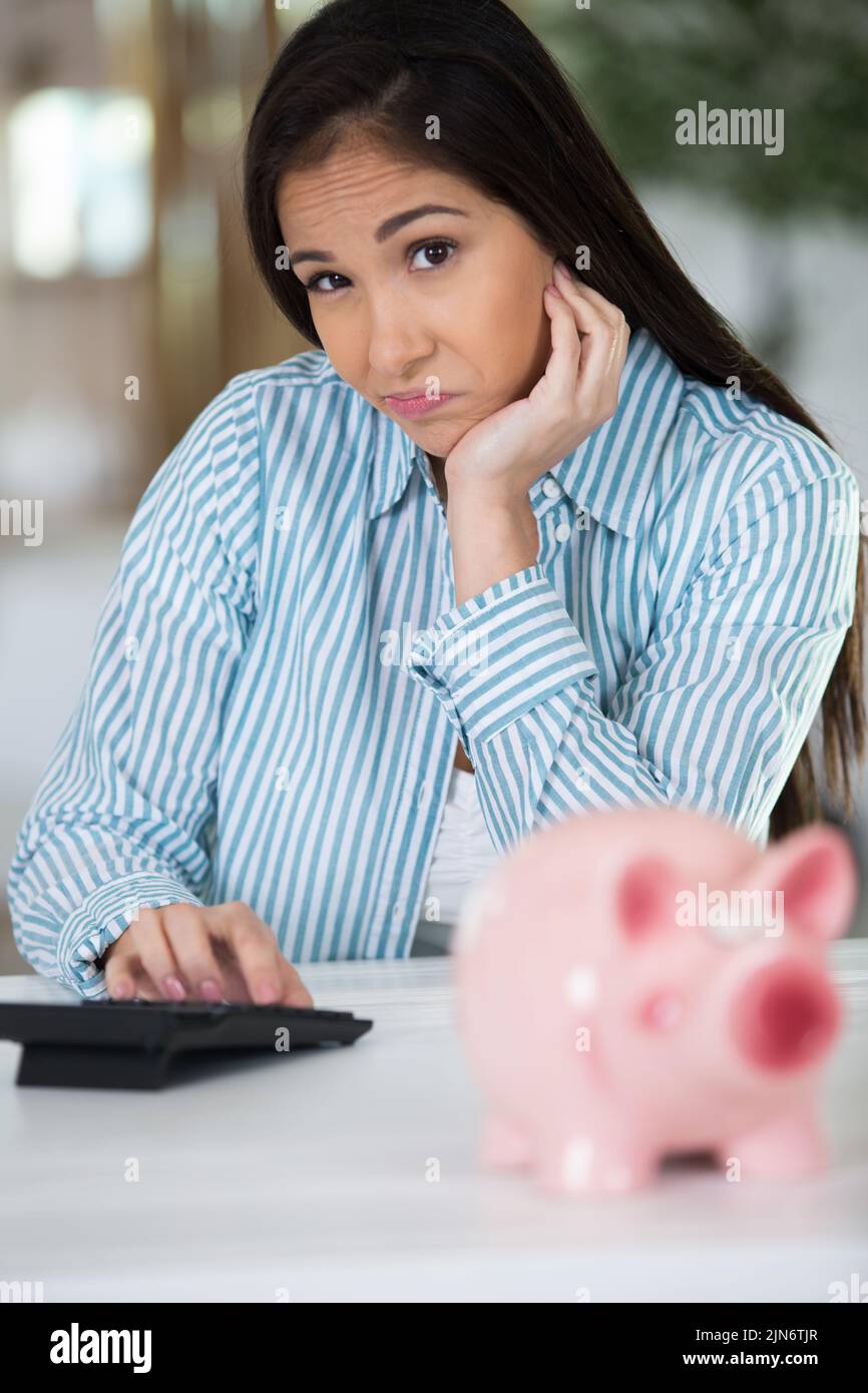 frustrated female looking at piggy bank Stock Photo
