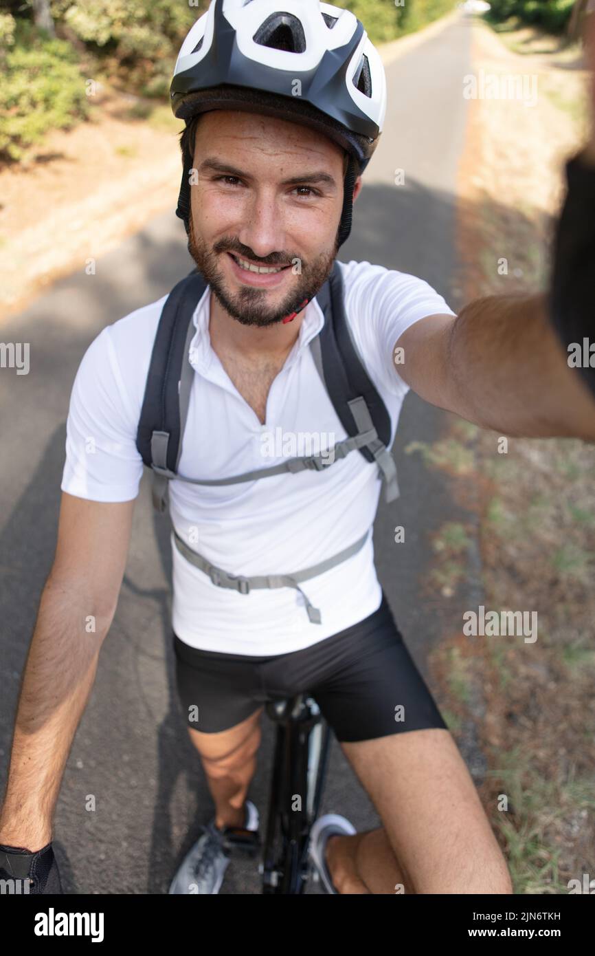 serious male cyclist in sports equipment taking photo of himself Stock Photo