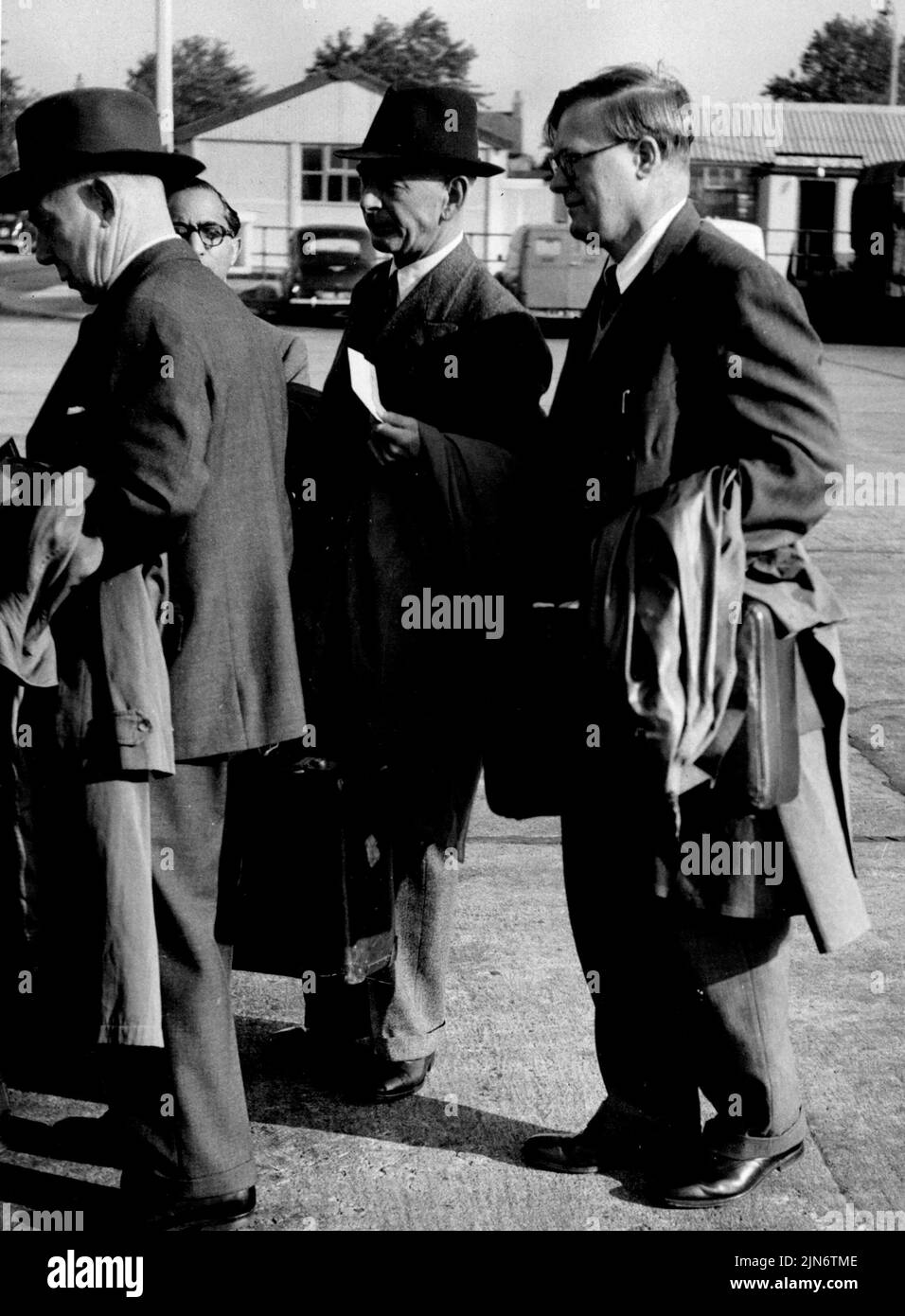 'Mr. Elmhurst' Leaves England:Last man in a line at London Airport yesterday ... The Sunday Express catches a picture of one of Britain's best protected Rush-Hush celebrities - Mr. Elmhurst.That is the name atom scientist Sir William Penney - Ministry of Supply Chief Superintendent of Armament Research - is using on a flight to Australia for the Big Bangs at Woomers. Members of his family were there to see him off. He was hurried through the customs; sat for several minutes in a private lounge. Before boarding the airliner he said: 'I expect to be back some time in November.' There was a 40 mi Stock Photo