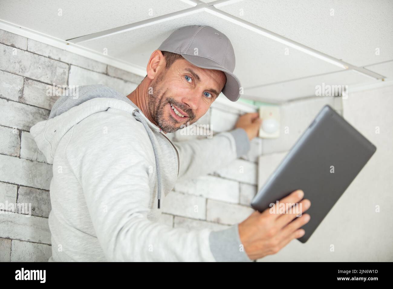 electrician with tablet computer installing alarm system indoors Stock Photo