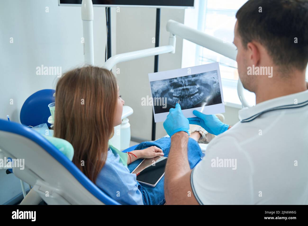 Dentist demonstrating caries on dental radiograph to female patient