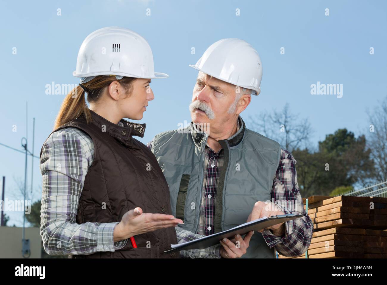 man and woman alking in hard hats Stock Photo