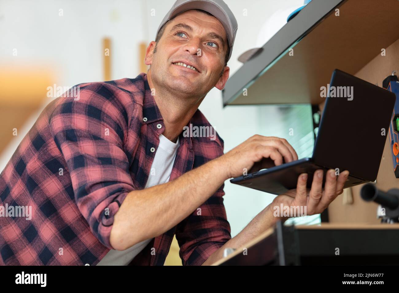 smiling carpenter using laptop at work in workshop Stock Photo