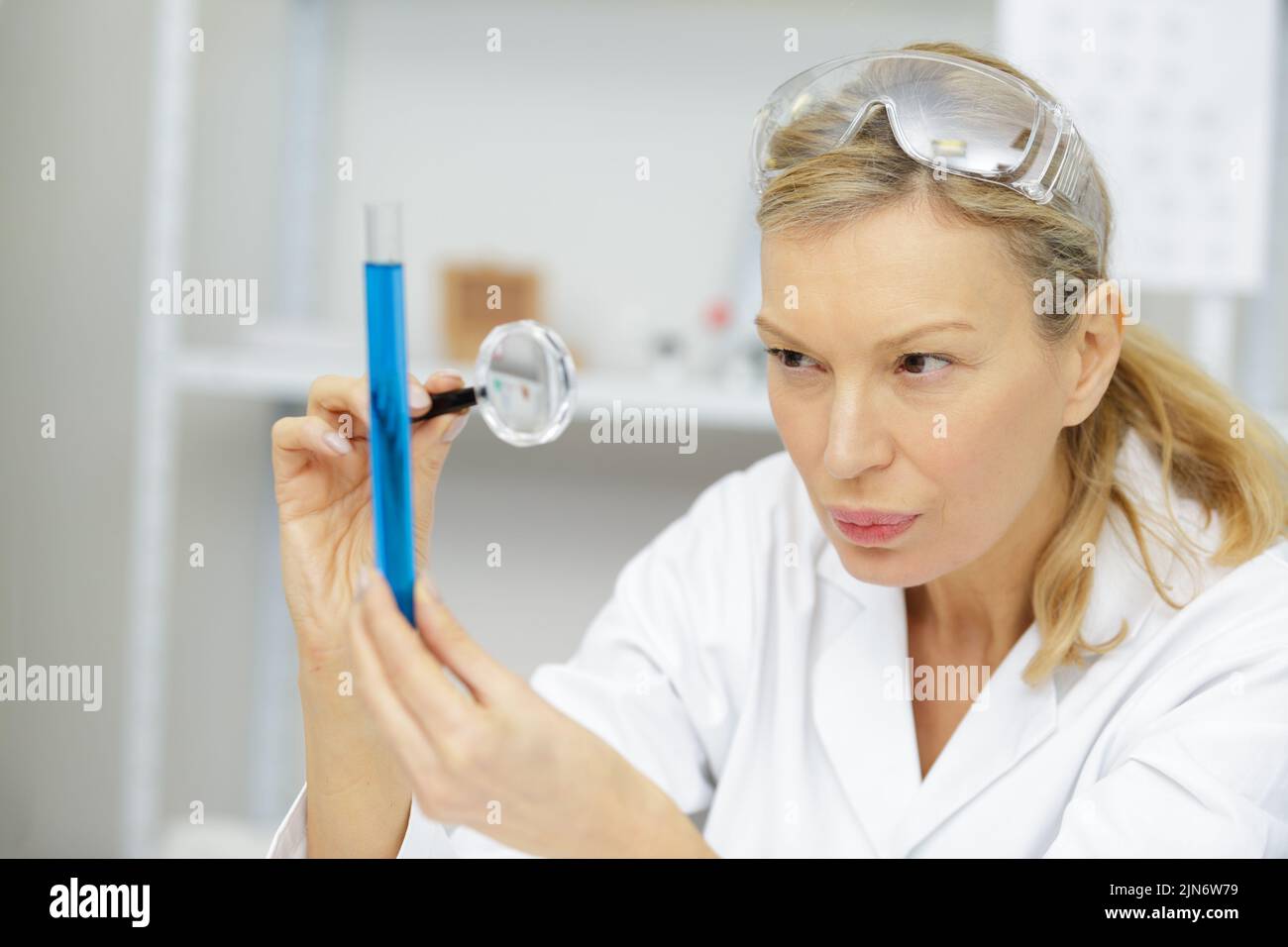 mature woman in lab coat using a magnifying glass Stock Photo Alamy