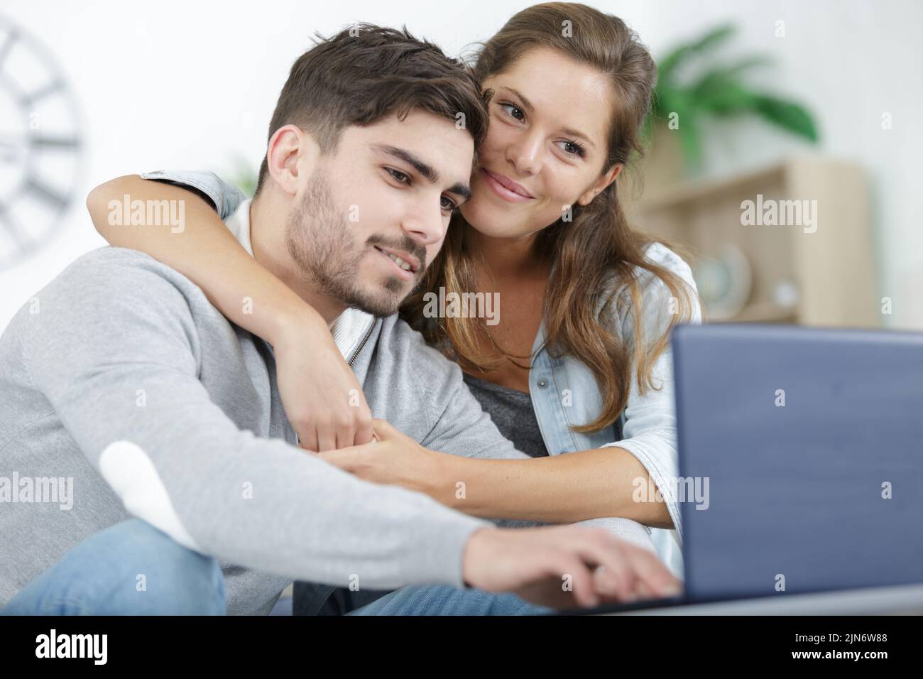 young man and woman smiling and browsing tablet and laptop Stock Photo