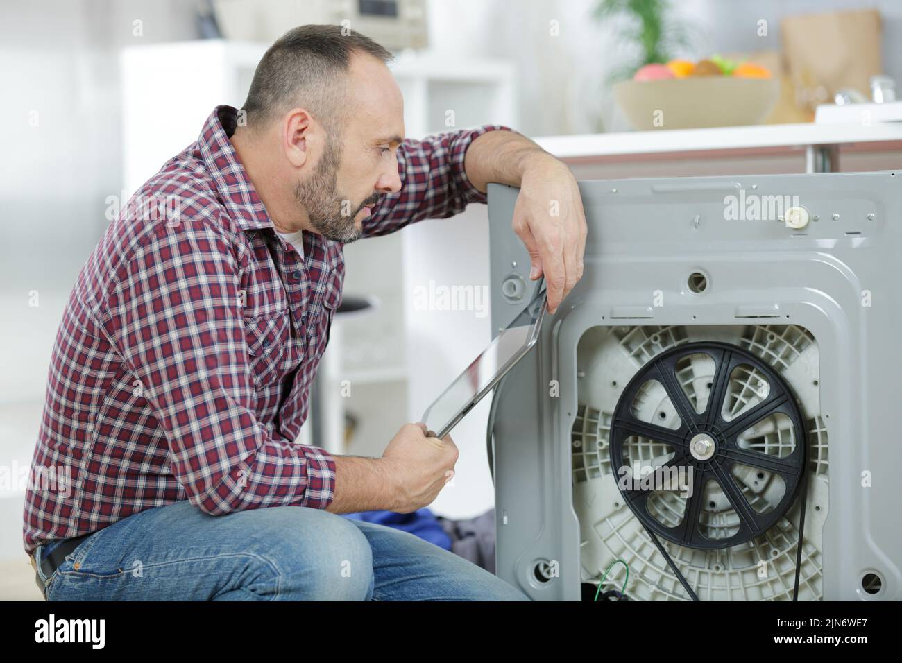 serviceman repairing washing machine looking at tablet Stock Photo