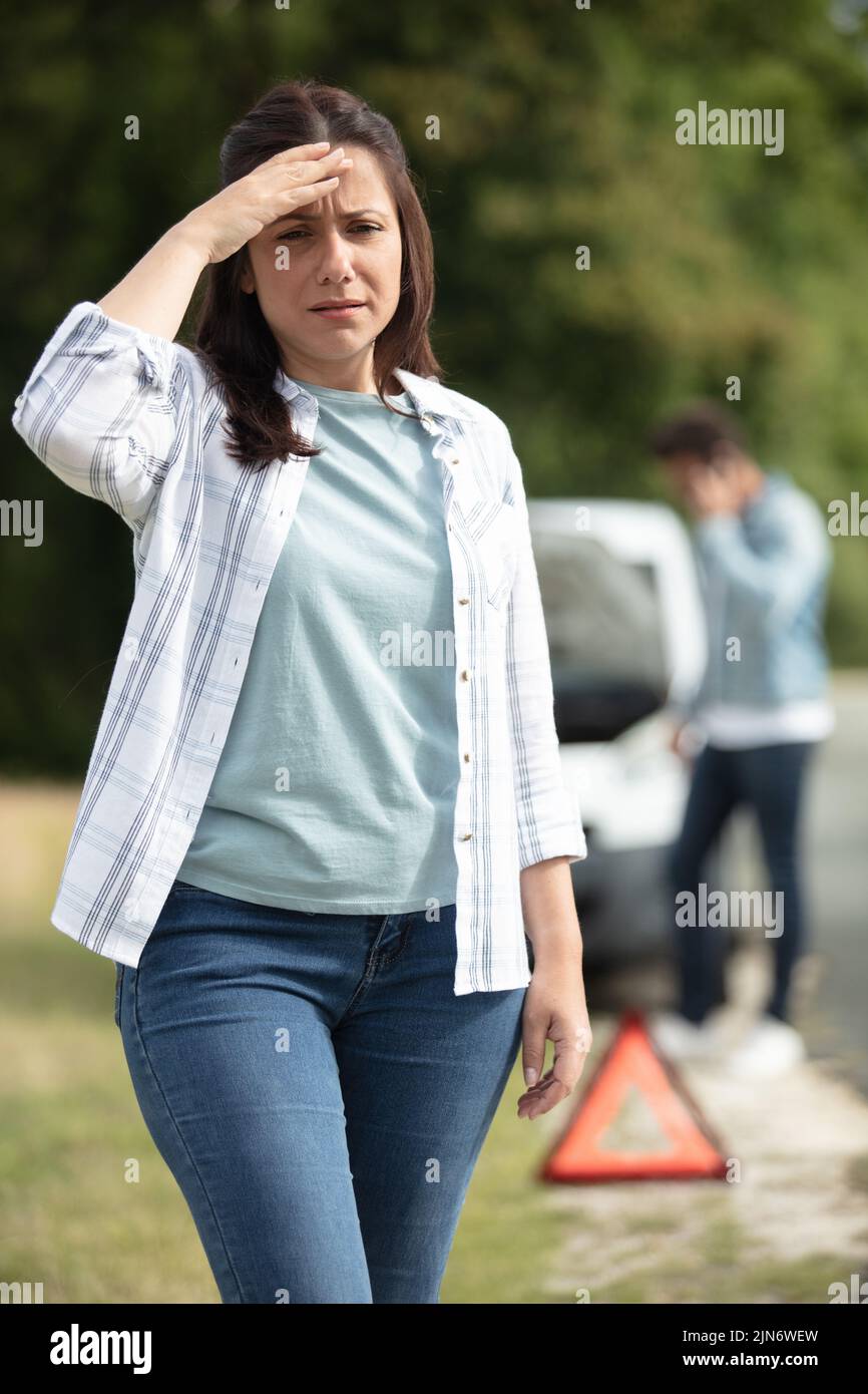 woman stands with emergency triangle against car Stock Photo